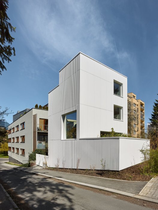 Bílý kvádr v pražské proluce ukazuje, že kvalitní architektura nevzniká velikostí, ale přesností návrhu. Rodinný dům Minimální maximum od ateliéru Stempel Tesař architekti pracuje s extrémně omezeným pozemkem, posunutými podlažími, absencí chodby a výrazným kontrastem bílé hliníkové fasády, pohledového betonu a ořechového dřeva. Stavba nominovaná na Českou cenu za architekturu je ukázkou toho, jak lze z minima prostoru vytvořit plnohodnotný, promyšlený a výtvarně silný domov.