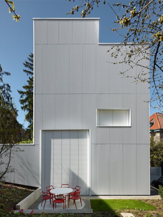 Bílý kvádr v pražské proluce ukazuje, že kvalitní architektura nevzniká velikostí, ale přesností návrhu. Rodinný dům Minimální maximum od ateliéru Stempel Tesař architekti pracuje s extrémně omezeným pozemkem, posunutými podlažími, absencí chodby a výrazným kontrastem bílé hliníkové fasády, pohledového betonu a ořechového dřeva. Stavba nominovaná na Českou cenu za architekturu je ukázkou toho, jak lze z minima prostoru vytvořit plnohodnotný, promyšlený a výtvarně silný domov.