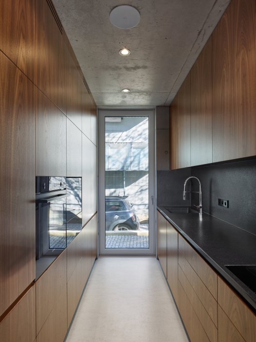 Bílý kvádr v pražské proluce ukazuje, že kvalitní architektura nevzniká velikostí, ale přesností návrhu. Rodinný dům Minimální maximum od ateliéru Stempel Tesař architekti pracuje s extrémně omezeným pozemkem, posunutými podlažími, absencí chodby a výrazným kontrastem bílé hliníkové fasády, pohledového betonu a ořechového dřeva. Stavba nominovaná na Českou cenu za architekturu je ukázkou toho, jak lze z minima prostoru vytvořit plnohodnotný, promyšlený a výtvarně silný domov.