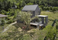Černá dřevěná fasáda dodává domu střídmý a sebevědomý výraz, zatímco velká okna ho propojují se zahradou.