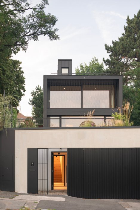 Na prudce svažité parcele nad pražskou kotlinou vznikl dům, který se okolním vilám nesnaží přizpůsobit. Black House od ateliéru Machar Teichman působí zvenku jako černá železobetonová krabice opláštěná titanzinkem, uvnitř se ale otevírá světlu, zahradě a panoramatickým výhledům na Prahu. Prohlédněte si současnou vilu, jejíž největší síla je v přesném využití složitého pozemku.