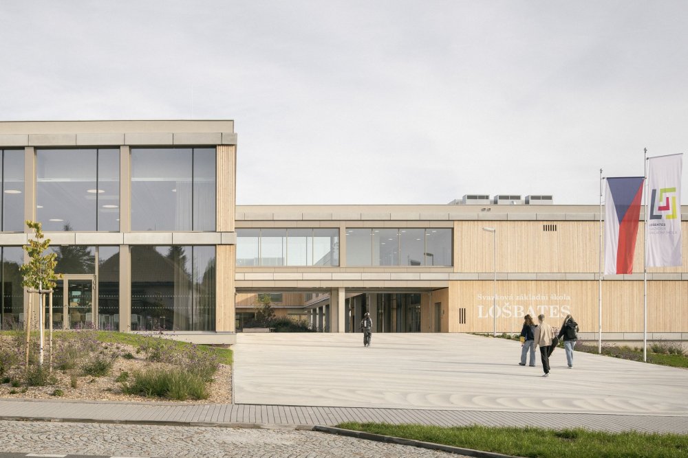 Svazková škola LOŠBATES v Louňovicích ukazuje, že kvalitní architektura nemusí být výsadou velkých měst. Nová školní budova vznikla jako odpověď na rostoucí potřebu vzdělávacích kapacit v menších obcích v zázemí Prahy. Nejde jen o další školu, ale o veřejnou stavbu, která dětem nabízí současné prostředí pro učení a obcím dává nový společný bod.