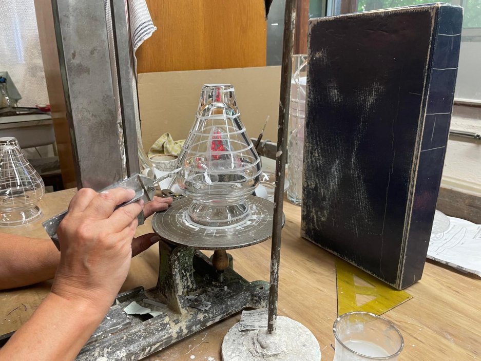 Ve sklárně se stále fouká sklo tradiční píšťalou, výrobky se odlévají do dřevěných forem a zkušená kreslička před broušením ručně vyznačuje každý řez. Za historickou kulisou se však odehrává tvrdý průmyslový byznys