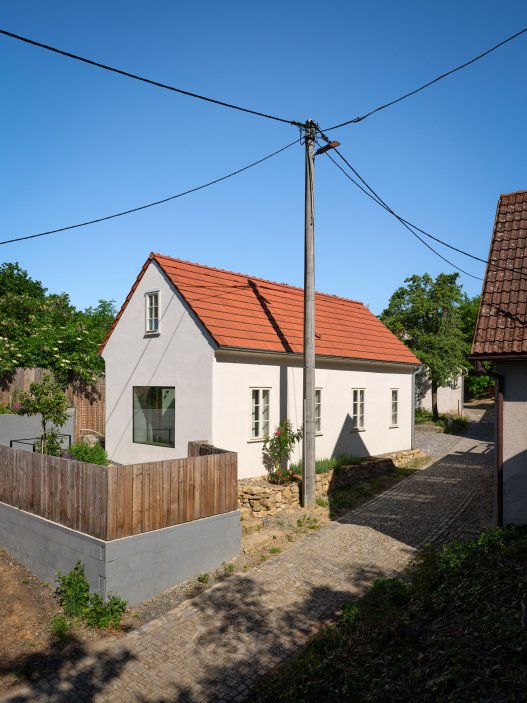 Bukovanský domeček od studia SENAA ukazuje, jak může současná architektura fungovat v historickém vesnickém prostředí. Novostavba respektuje původní stopu domu i charakter úzké vinařské uličky, uvnitř ale nabízí moderní dispozici, velkoformátová okna, betonové schodiště i staré trámy zachráněné z pražského Karlína.