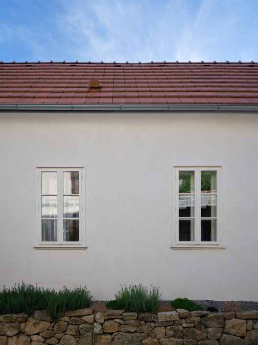 Bukovanský domeček od studia SENAA ukazuje, jak může současná architektura fungovat v historickém vesnickém prostředí. Novostavba respektuje původní stopu domu i charakter úzké vinařské uličky, uvnitř ale nabízí moderní dispozici, velkoformátová okna, betonové schodiště i staré trámy zachráněné z pražského Karlína.