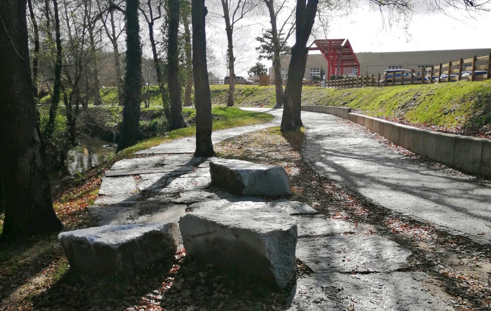 Leça Green Corridor pracuje v úplně jiném měřítku. Zelený koridor měří 48 kilometrů, propojuje čtyři municipality a vytváří 22 hektarů lineárního veřejného prostoru. Vedle pěšího a cyklistického pohybu řeší obnovu krajiny, odolnost vůči vodě a propojení měst podél řeky Leça. Veřejný prostor se tu mění z jednoho náměstí či parku v rozsáhlou krajinnou infrastrukturu.
