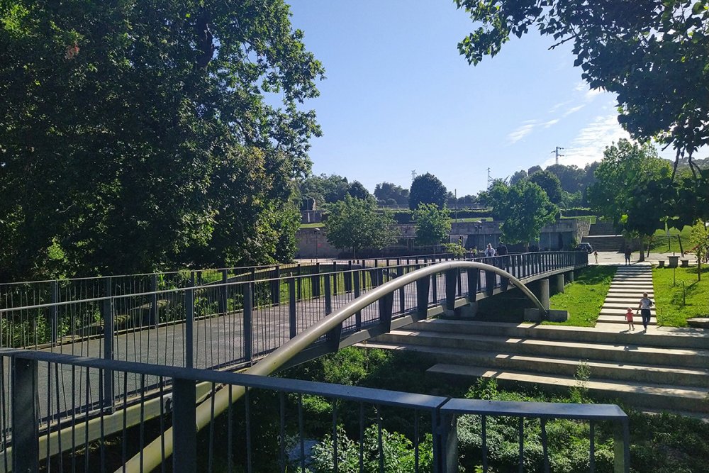 Leça Green Corridor pracuje v úplně jiném měřítku. Zelený koridor měří 48 kilometrů, propojuje čtyři municipality a vytváří 22 hektarů lineárního veřejného prostoru. Vedle pěšího a cyklistického pohybu řeší obnovu krajiny, odolnost vůči vodě a propojení měst podél řeky Leça. Veřejný prostor se tu mění z jednoho náměstí či parku v rozsáhlou krajinnou infrastrukturu.