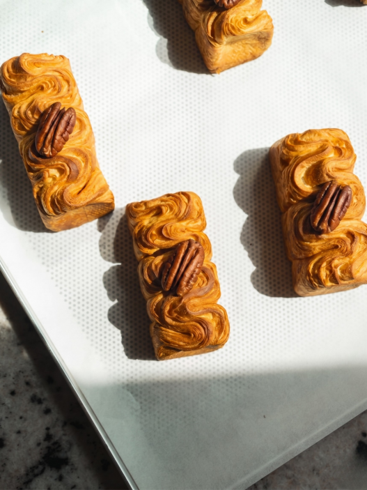 Plissé Pecan Praliné označuje prémiové sladké pečivo, které kombinuje francouzskou cukrářskou techniku s náplní z karamelizovaných ořechů. 