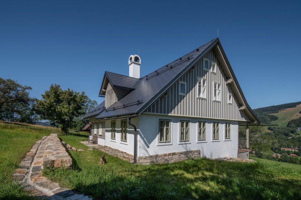 Stará krkonošská roubenka v Rokytnici nad Jizerou prošla citlivou rekonstrukcí, která zachovala maximum původních prvků a zároveň ji přizpůsobila současnému bydlení. Uvnitř vznikly tři apartmány, sauna a nové zázemí, dům si ale ponechal své nepravidelnosti, původní kámen i charakter horské chalupy. Za proměnou stojí architektka Barbora Šlechta Vlčková a studio BARAAK Architects.