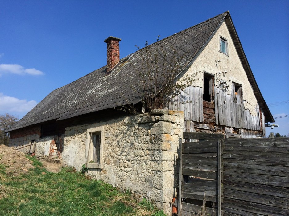 V Lipné u Hazlova, v krajině bývalých Sudet nedaleko německých hranic, stojí vedle sebe roubený statek po babičce majitele a kamenný dům z roku 1852. Obě stavby prošly citlivou obnovou, která zachovala původní dřevo a kámen a doplnila je současnou architekturou. Dnes tvoří komorní areál, kde hlavní roli hrají historie, krajina a klid.