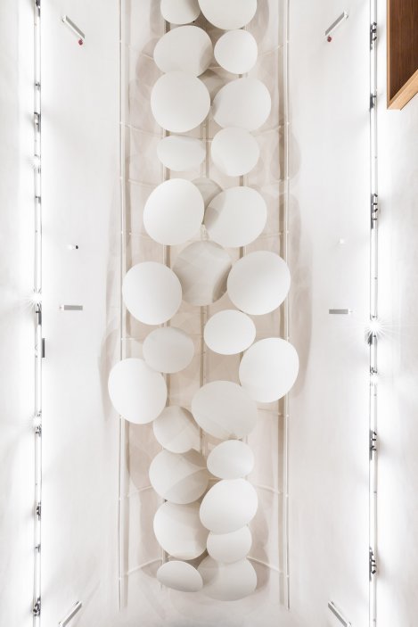 Nejvýraznějším prvkem interiéru jsou lehké bílé akustické baldachýny zavěšené pod stropem.