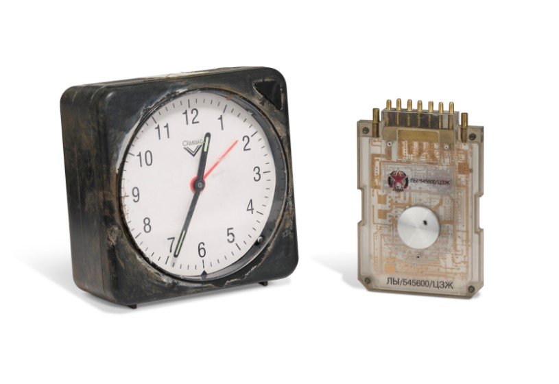 Speciální hodiny ve vlastnictví „M“ v podání Judi Denchové v Jeden svět nestačí (1999), odhadovaná cena tři až pět tisíc liber.