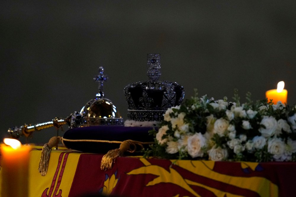 Katafalk s ostatky zesnulé královny Alžběty II. s korunou a žezlem osvícené pietní svící ve Westminsterském paláci.