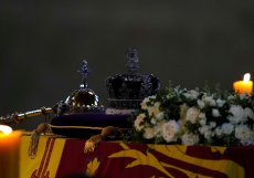 Katafalk s ostatky zesnulé královny Alžběty II. s korunou a žezlem osvícené pietní svící ve Westminsterském paláci.
