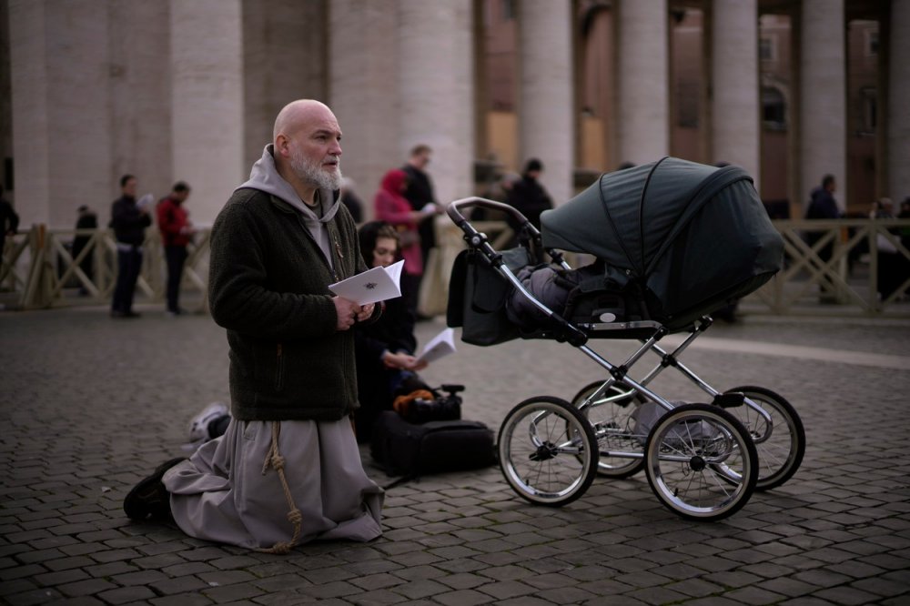 Muž na Svatopetrském náměstí ve Vatikánu se modlí během pohřbu papeže Benedikta XVI.