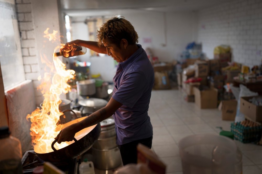 Julio Calizaida flambuje steak v přístřešku, kde přebývají mimoměstští protivládní demonstranti v Limě v Peru ve středu 8. února 2023. Demonstranti se sjížděli do peruánské metropole, přičemž mnozí z nich cestovali do Limy ze vzdálených regionů, s cílem žádat rezignaci prezidentky Diny Boluarteové.