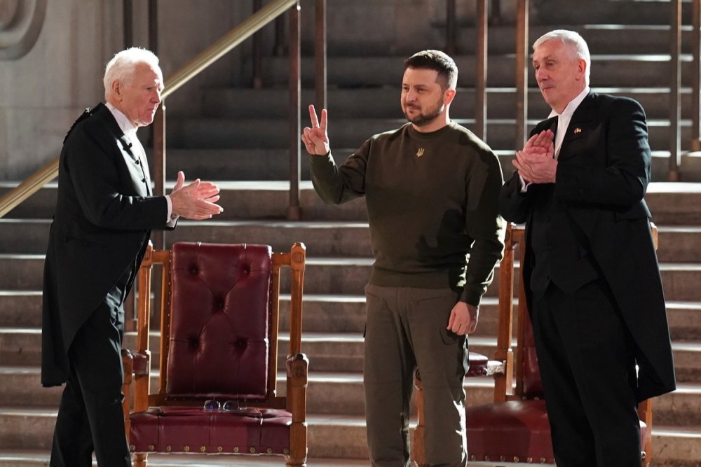 Ukrajinský prezident Volodymyr Zelenskyj s gestem V jako „victory“ ve chvíli, kdy mu aplaudovali předseda Dolní sněmovny Sir Lindsay Hoyle (vpravo) a předseda Sněmovny lordů lord McFall (vlevo) po svém projevu k poslancům ve Westminster Hall v Londýně během své první návštěvy Spojeného království od ruské invaze na Ukrajinu, ve středu 8. února. 2023.