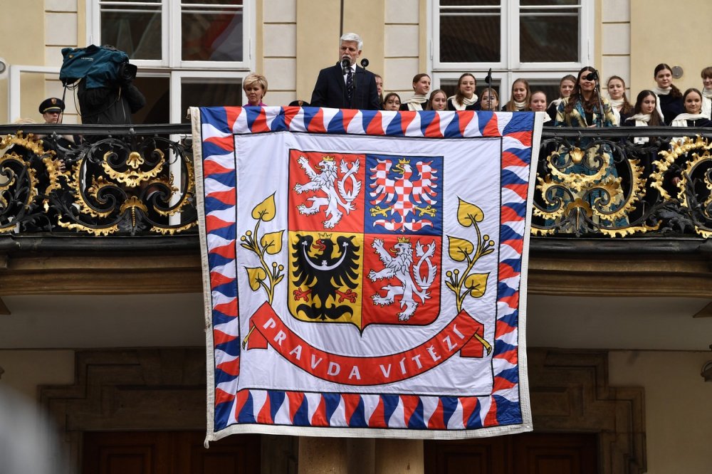 Inaugurace nově zvoleného prezidenta Petra Pavla, 9. března 2023, Pražský hrad. Prezident Petr Pavel a první dáma Eva Pavlová zdraví přihlížející z balkonu na třetím hradním nádvoří. V popředí visí prezidentská standarta, kterou v roce 2015 skupina Ztohoven vyměnila za rudé trenýrky na protest proti politice tehdejšího prezidenta Miloše Zemana.