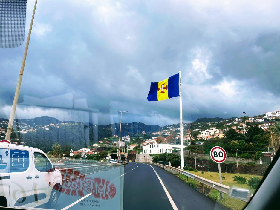 Vlajka Madeiry vás uvítá hned u letiště. Vlajka tohoto autonomního regionu Portugalska má tři svislé pruhy – žlutý je uprostřed a po stranách jsou modré pruhy. Uprostřed žlutého pruhu je bílo-červený kříž rytířů Kristova řádu, který má symbolizovat madeirský separatismus. Modrožluté svislé pruhy pak představují Atlantský oceán obklopující ostrov, ale i krásu, jasnost a klid.