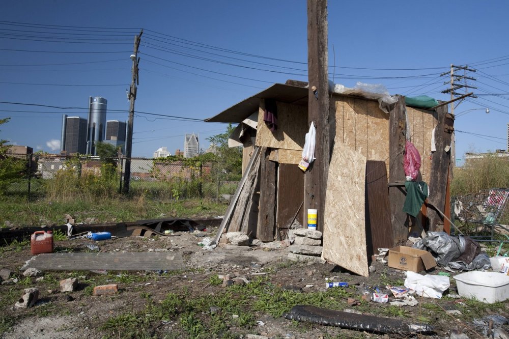 Obydlí bezdomovce se sídlem automobilky General Motors v pozadí, Detroit.