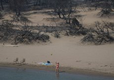 Ani spáleniště neodradilo lidi od pobytu na pobřeží a hraní si s míčem, jako ve čtvrtek 27. července 2023 na pláži poblíž vesnice Gennadi na ostrově Rhodos v jihovýchodním Řecku v Egejském moři.